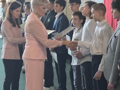 Uczniowie i nauczyciele odbierający nagrody i stojący na tle polskiej flagi