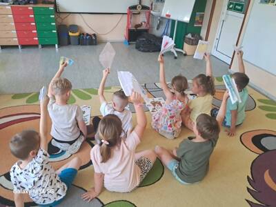 Dzieci siedzą przy stoliku i na podłodze