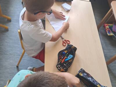 Dzieci siedzą przy stoliku i na podłodze
